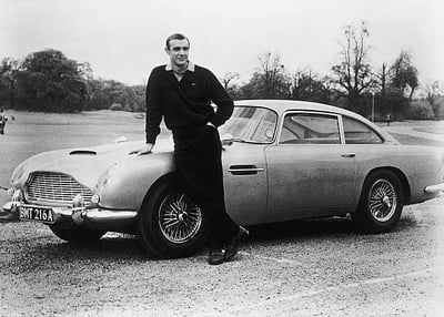 Sean Connery as James Bond, product placement pioneer, in a classic pose with his Aston Martin and tailored suit, showcasing the sophisticated brand integrations that made the character a powerful marketing force.